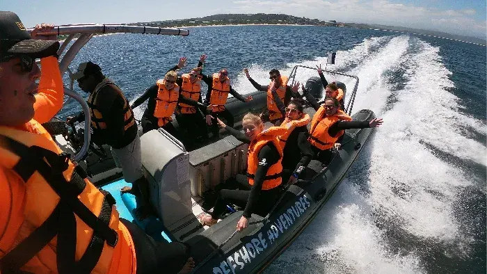 Guests in life jackets on the boat with the wake behind